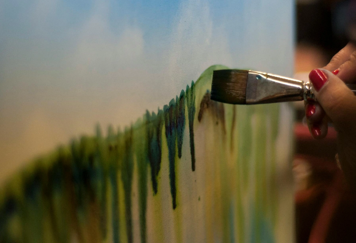 A person painting with a brush on the side of a wall.